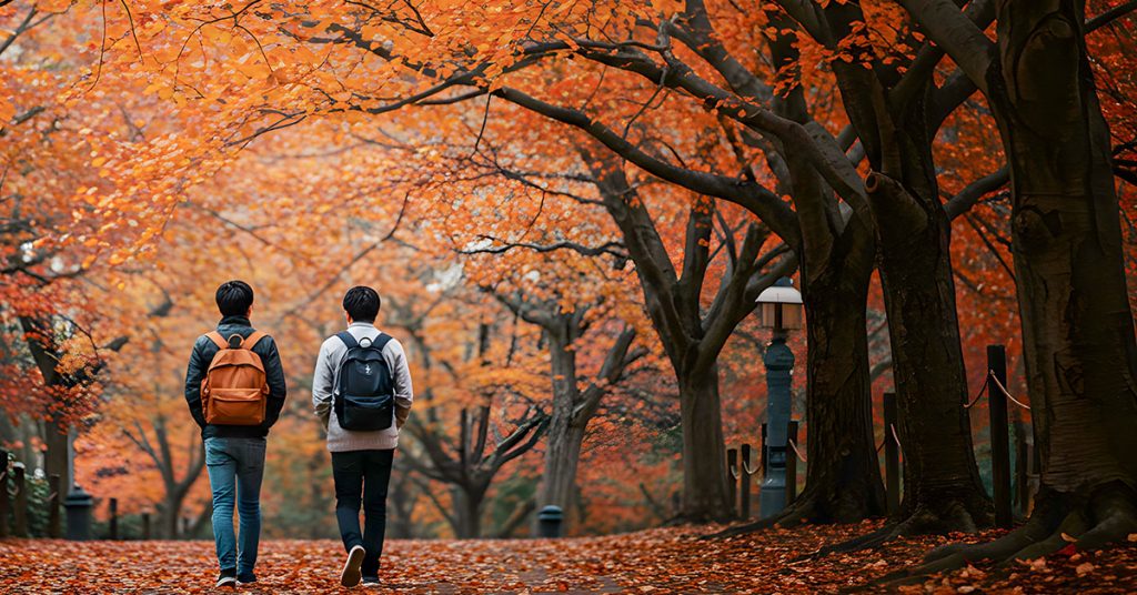 Two students walking thru campus with autumn leaves